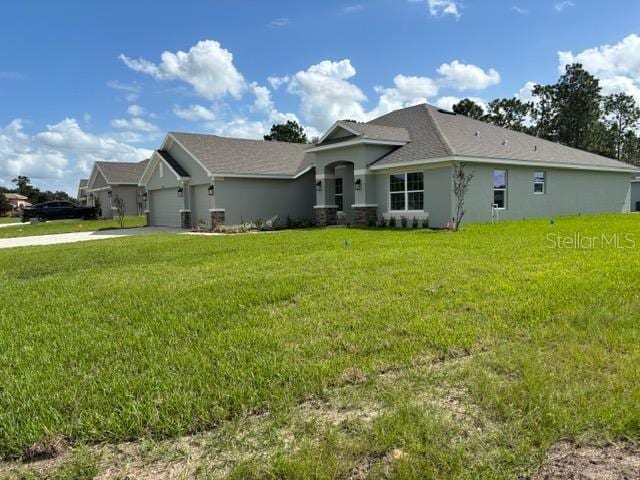 view of front of house with an attached garage, a front lawn, stucco siding, and driveway