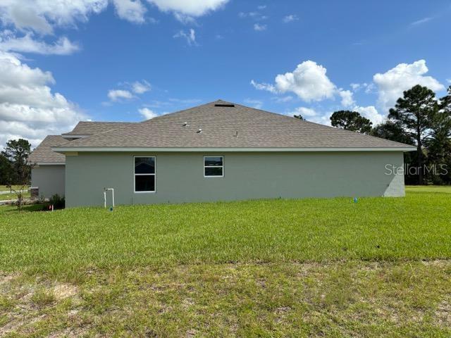 back of property featuring stucco siding and a yard