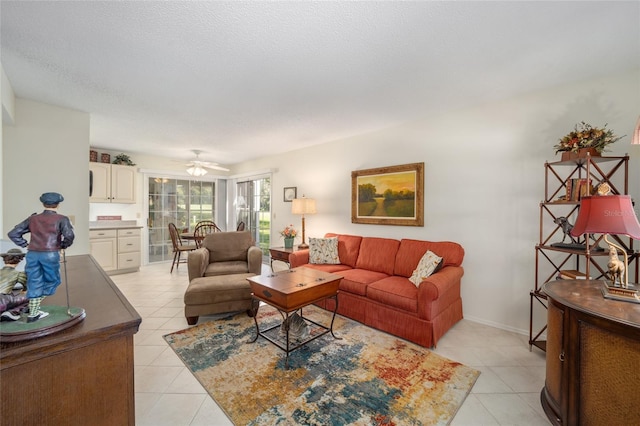 living room featuring a textured ceiling, light tile patterned floors, and ceiling fan