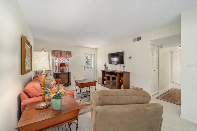 living room featuring a textured ceiling and light tile patterned floors