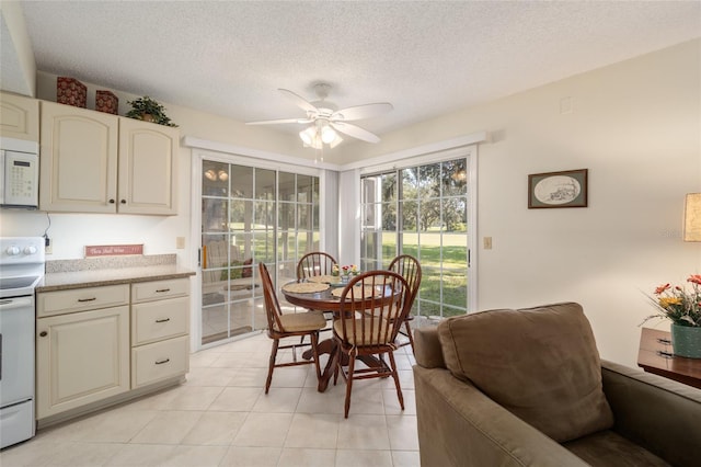 tiled dining area with ceiling fan and a textured ceiling