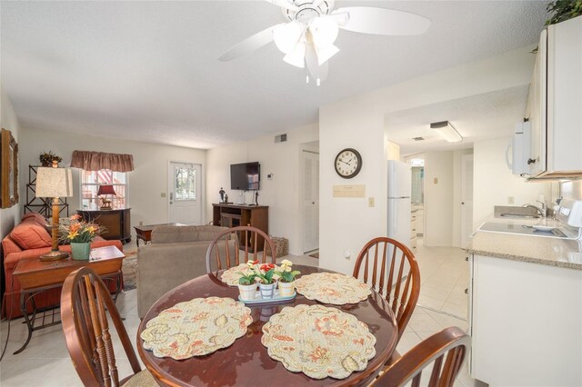 dining room with ceiling fan, sink, light tile patterned floors, and a textured ceiling