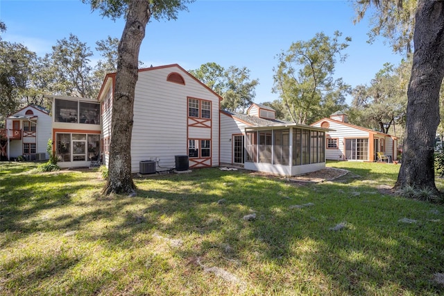 rear view of property with a sunroom, a lawn, and central AC unit