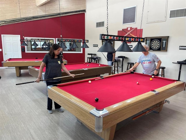 recreation room with a towering ceiling and hardwood / wood-style flooring