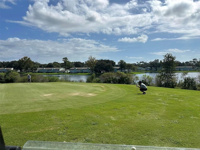 view of property's community with a water view and a lawn