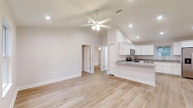 kitchen featuring white cabinets, light stone countertops, kitchen peninsula, stainless steel appliances, and light wood-type flooring