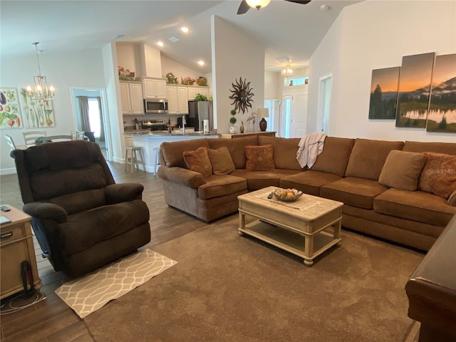 living room featuring high vaulted ceiling, ceiling fan with notable chandelier, and hardwood / wood-style floors