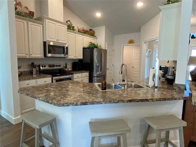 kitchen with a breakfast bar, sink, white cabinetry, appliances with stainless steel finishes, and kitchen peninsula