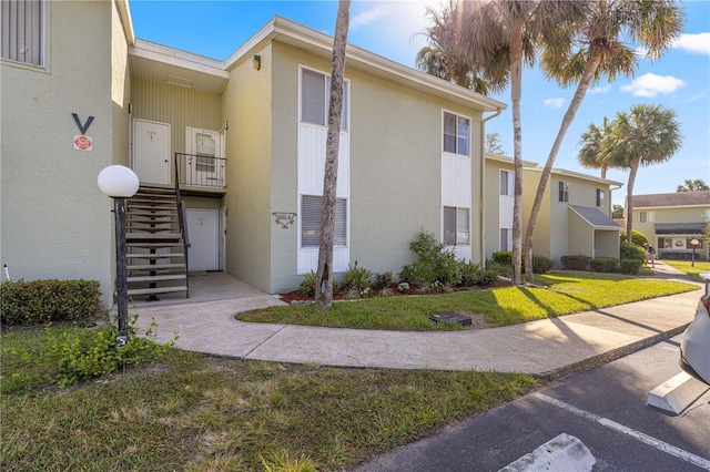 551 Fairways Dr Unit A, Ocala, FL 34472 - view of side of property with stairway, stucco siding, uncovered parking, and a yard