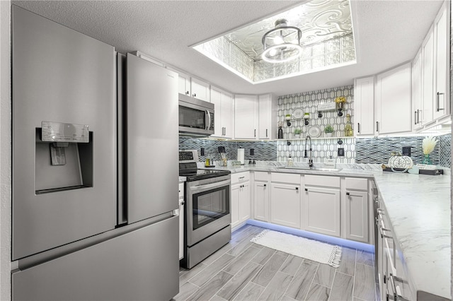 kitchen featuring backsplash, white cabinetry, a textured ceiling, sink, and stainless steel appliances