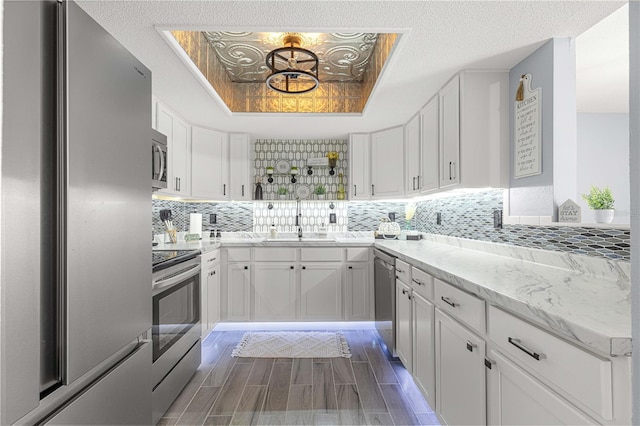 551 Fairways Dr Unit A, Ocala, FL 34472 - kitchen with decorative backsplash, stainless steel appliances, white cabinets, a sink, and a tray ceiling