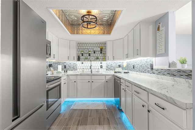 kitchen featuring decorative backsplash, white cabinets, a textured ceiling, sink, and stainless steel appliances