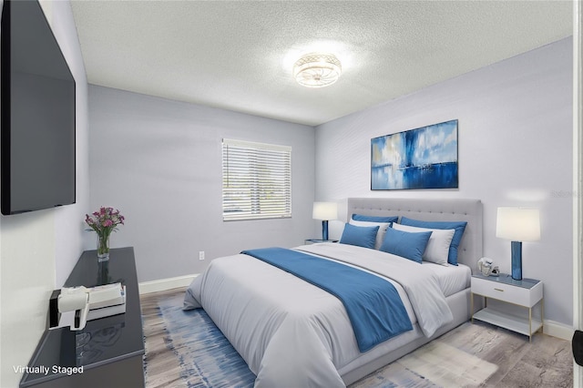 bedroom with light hardwood / wood-style floors and a textured ceiling