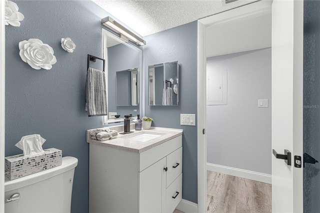 bathroom with vanity, toilet, a textured ceiling, and hardwood / wood-style floors