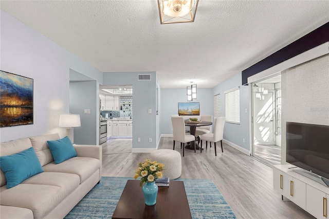 living room with a textured ceiling and light wood-type flooring