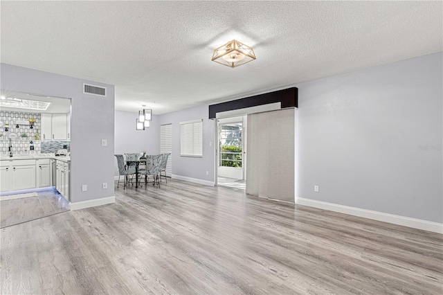 unfurnished living room featuring light hardwood / wood-style floors and a textured ceiling