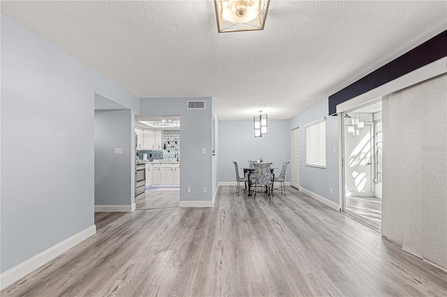 unfurnished dining area featuring a textured ceiling and light hardwood / wood-style flooring