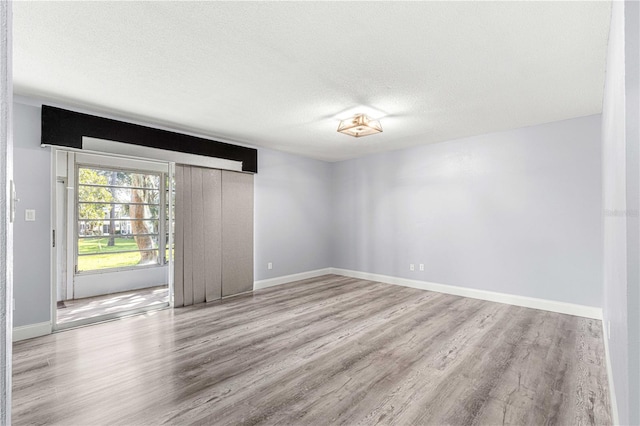 spare room with light hardwood / wood-style floors and a textured ceiling