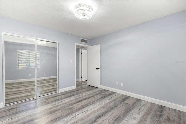 unfurnished bedroom featuring a closet, light hardwood / wood-style floors, and a textured ceiling