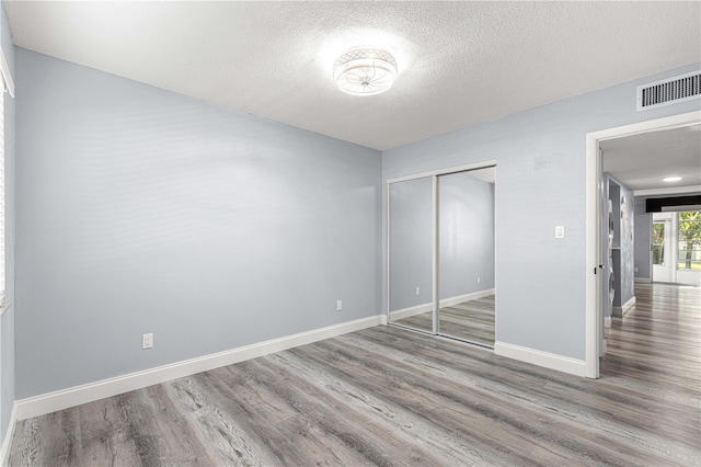 unfurnished bedroom with a closet, a textured ceiling, and wood-type flooring