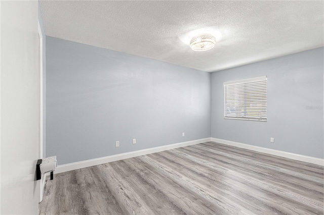 spare room with light hardwood / wood-style floors and a textured ceiling