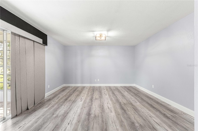 empty room with light hardwood / wood-style flooring and a textured ceiling