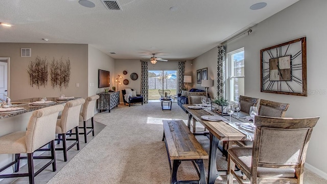 dining area featuring a textured ceiling, ceiling fan, and light colored carpet