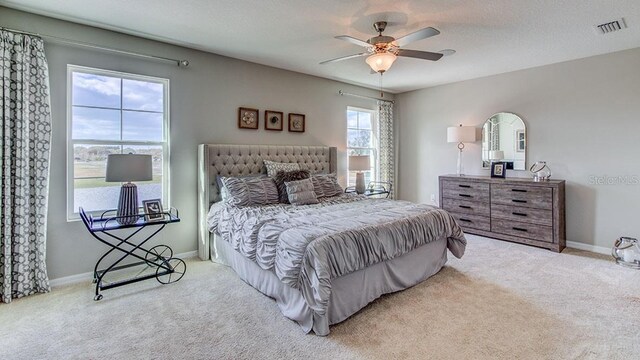 bedroom with light carpet, a textured ceiling, and ceiling fan