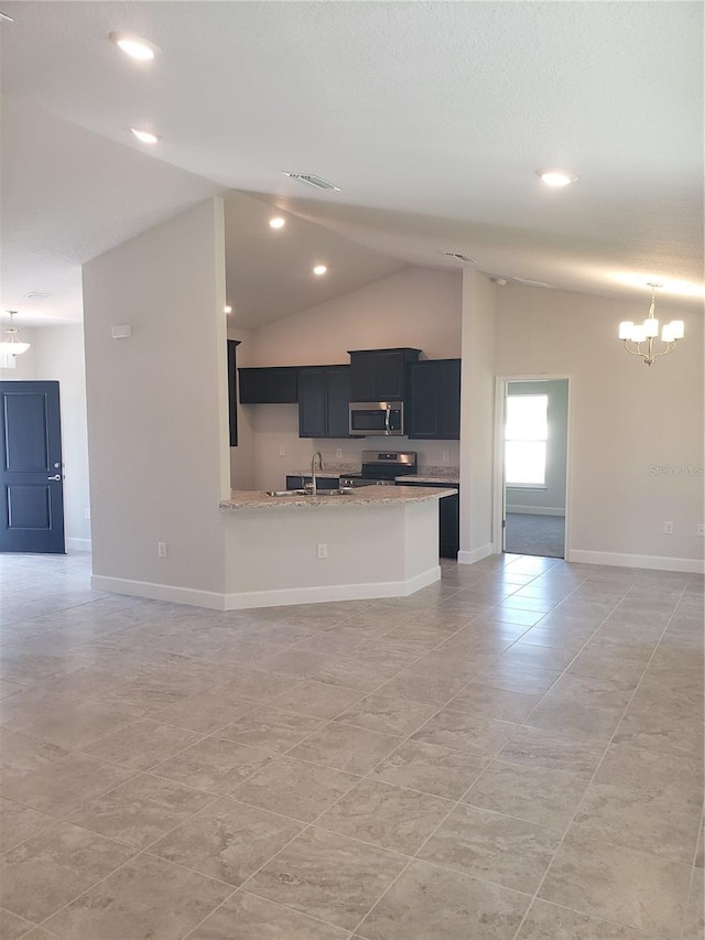 kitchen with light stone counters, stainless steel appliances, dark cabinets, and open floor plan