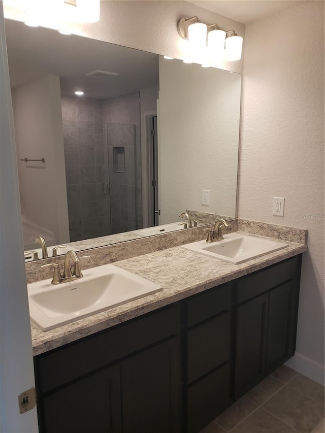 full bathroom featuring double vanity, tile patterned flooring, a sink, and a shower stall