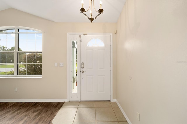 entryway featuring wood-type flooring, a chandelier, vaulted ceiling, and a healthy amount of sunlight