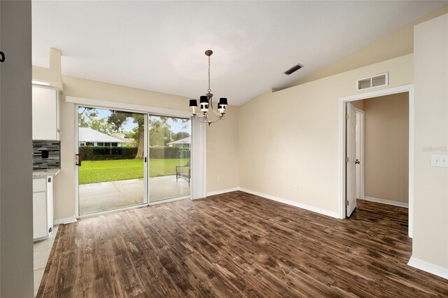 unfurnished dining area with dark hardwood / wood-style floors, vaulted ceiling, and an inviting chandelier