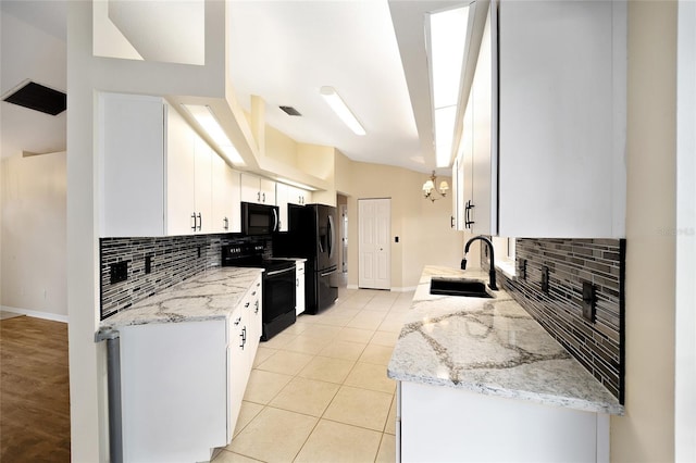 kitchen with light stone countertops, white cabinets, black appliances, and sink