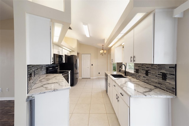 kitchen with white cabinetry, a sink, backsplash, black appliances, and vaulted ceiling