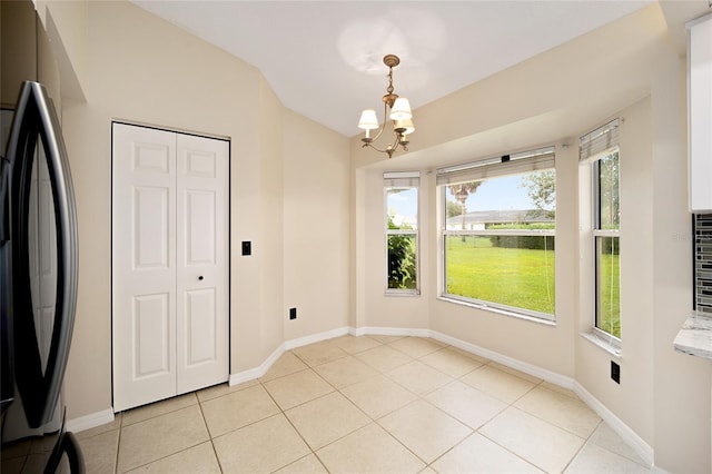 unfurnished dining area with a chandelier and light tile patterned floors