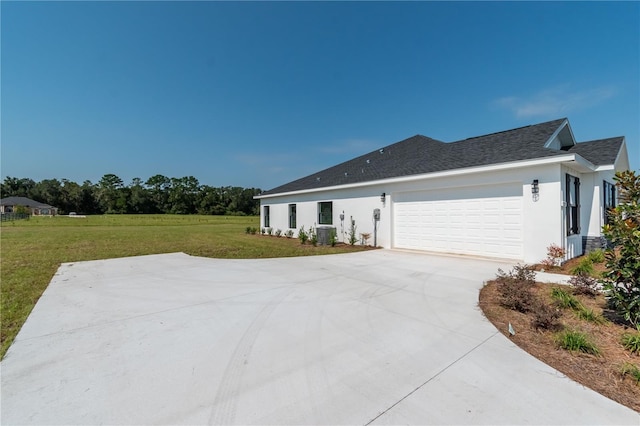 view of side of property featuring central AC, a yard, and a garage