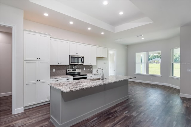 kitchen featuring dark hardwood / wood-style flooring, appliances with stainless steel finishes, an island with sink, white cabinetry, and sink