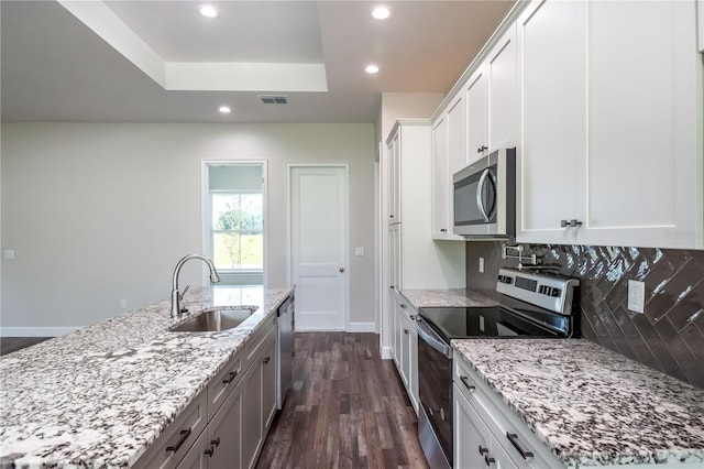 kitchen featuring appliances with stainless steel finishes, sink, white cabinetry, dark hardwood / wood-style floors, and a kitchen island with sink