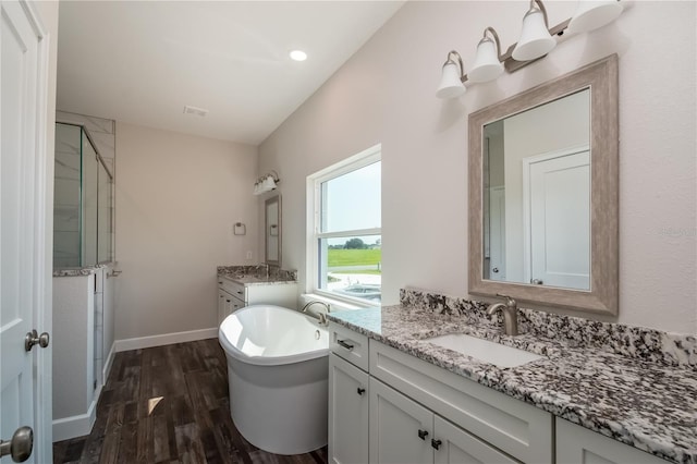 2073 NW 79th Loop, Ocala, FL 34475 - bathroom featuring a shower stall, wood finished floors, a freestanding tub, two vanities, and baseboards