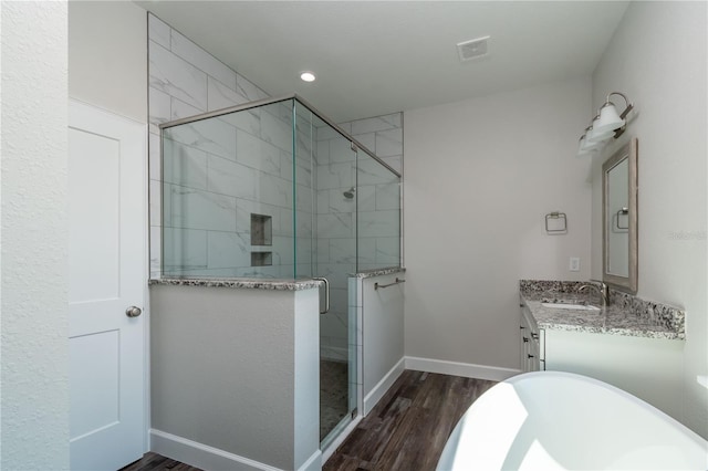 2073 NW 79th Loop, Ocala, FL 34475 - full bathroom featuring wood finished floors, a stall shower, baseboards, vanity, and a freestanding tub