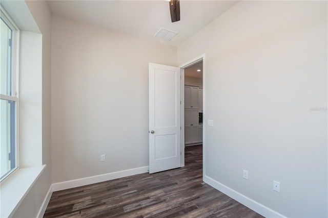 unfurnished room featuring dark wood-type flooring and a healthy amount of sunlight