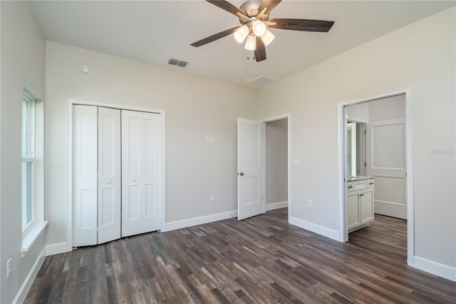 unfurnished bedroom with connected bathroom, a closet, dark wood-type flooring, and ceiling fan