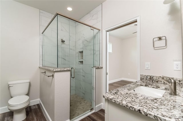 bathroom with toilet, a shower with shower door, hardwood / wood-style flooring, and vanity