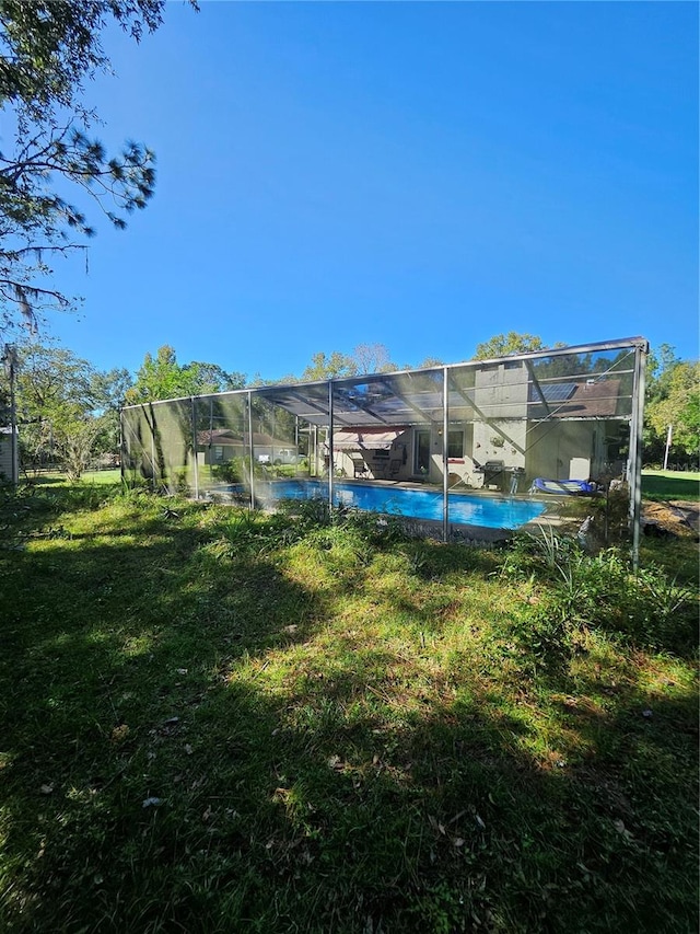 view of pool with a yard and glass enclosure