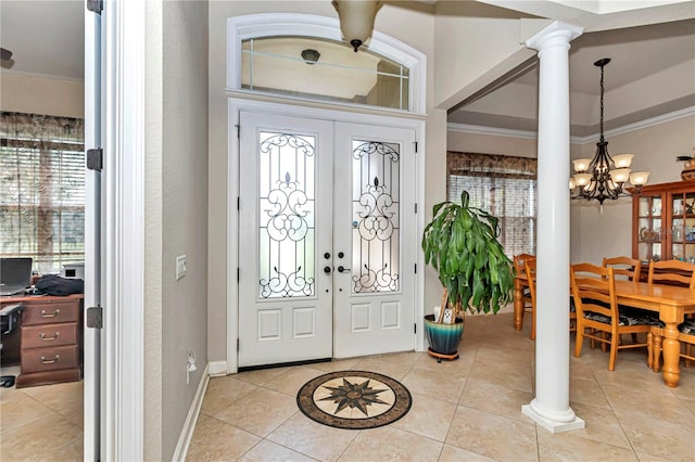 tiled foyer entrance with an inviting chandelier, ornamental molding, decorative columns, and plenty of natural light