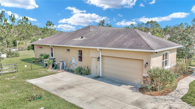 exterior space with central AC, a garage, and a lawn