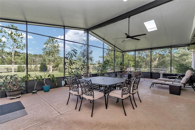 sunroom featuring vaulted ceiling with skylight, ceiling fan, and plenty of natural light