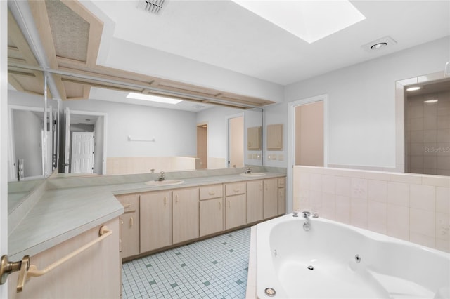 bathroom featuring a skylight, a washtub, vanity, and tile patterned flooring