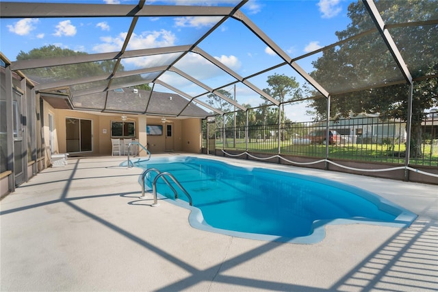 view of pool featuring glass enclosure, a patio area, and ceiling fan