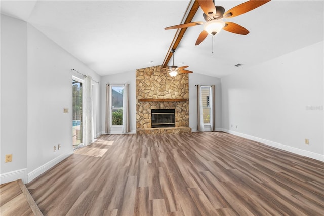 unfurnished living room with vaulted ceiling with beams, ceiling fan, a stone fireplace, and wood-type flooring